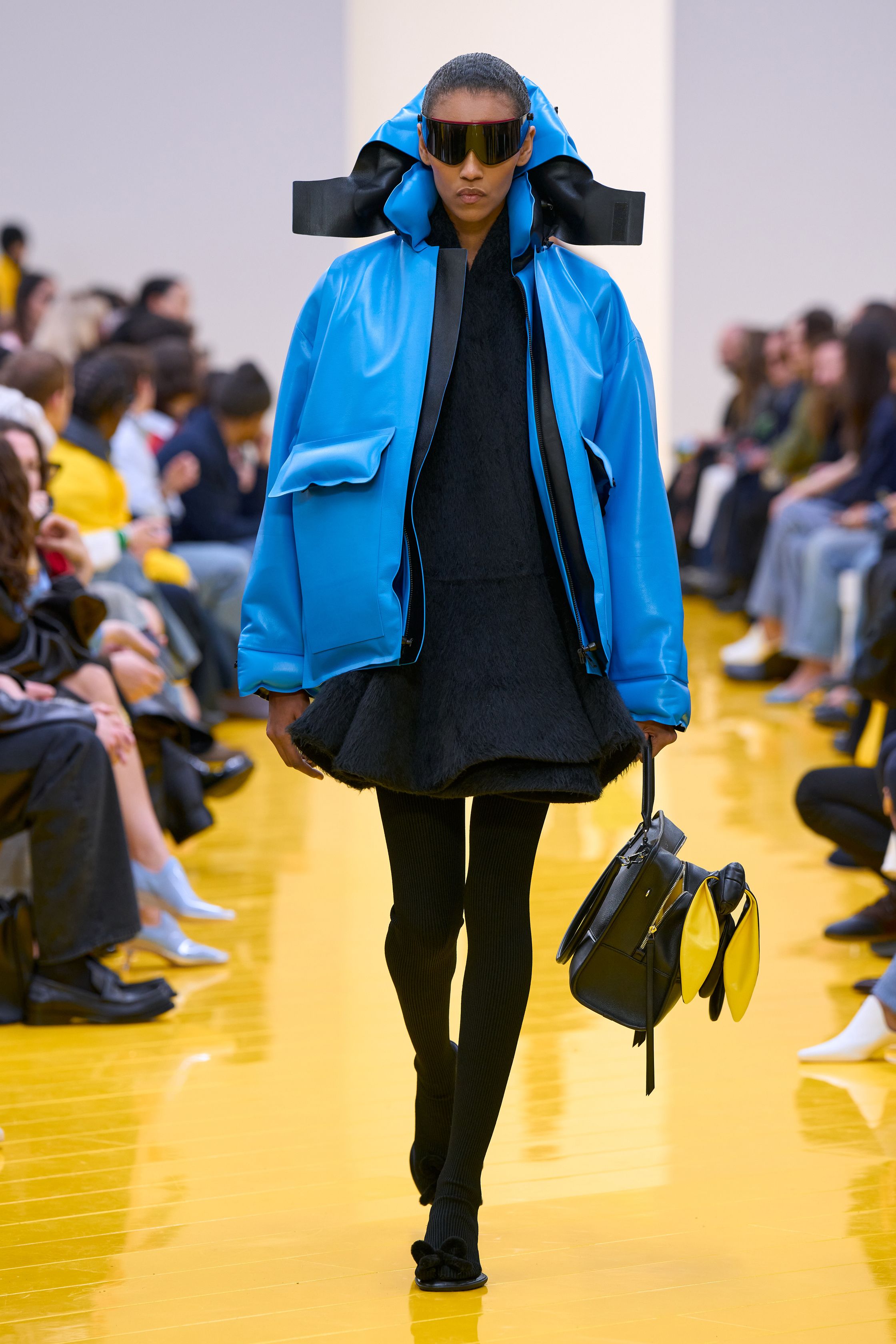 Jonathan Anderson 为 Loewe 带来一场充满艺术实验的秀：黄色地面与鲜明色彩形成强烈视觉舞台，极简廓形针织、雕塑化皮革外套、夸张毛绒结构和实验比例裙装共同构建一种“可穿戴雕塑”。从鲜黄、亮蓝到浓郁棕色毛绒，材质对比成为本季核心语言，既有幽默感也带有博物馆式艺术气质-顽石频道趋势研究